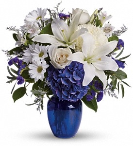 Lush blue hydrangeas, creamy crÃ¨me roses, pure white lilies, delicate alstroemeria, and fresh white chrysanthemums, this bouquet is complemented by fragrant eucalyptus, airy Limonium, and other seasonal greenery for a full, luxurious display.